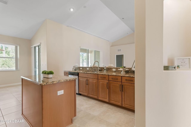 kitchen featuring light stone countertops, a kitchen island, stainless steel dishwasher, and vaulted ceiling