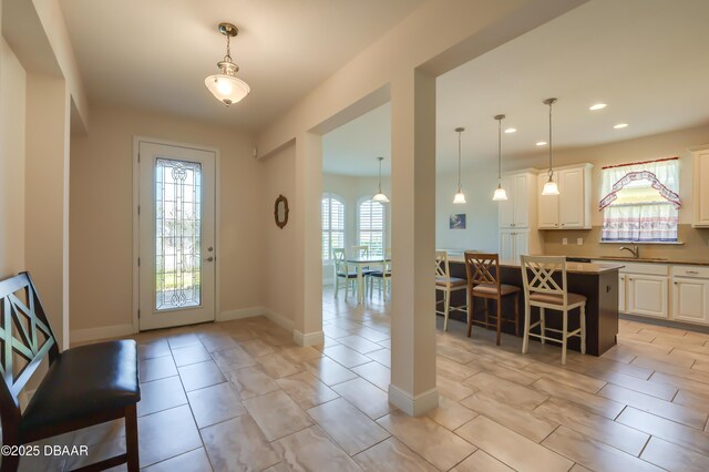 kitchen featuring pendant lighting, a breakfast bar area, a center island, light stone counters, and white cabinets