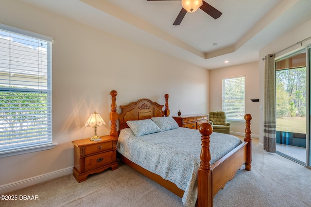 carpeted bedroom featuring ceiling fan, a raised ceiling, and access to outside