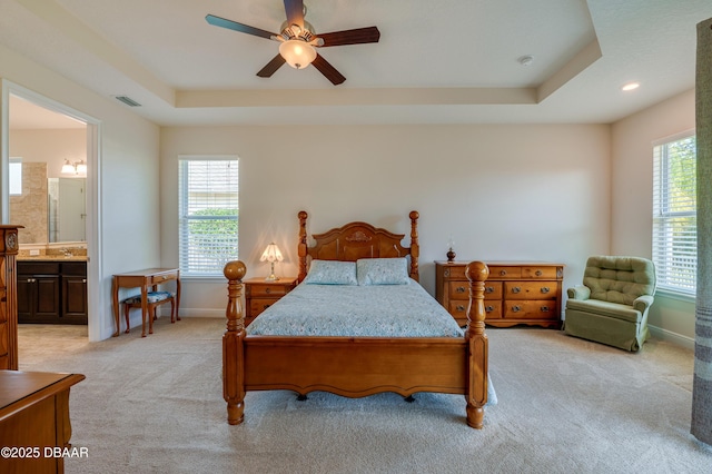 carpeted bedroom with multiple windows, connected bathroom, and a tray ceiling