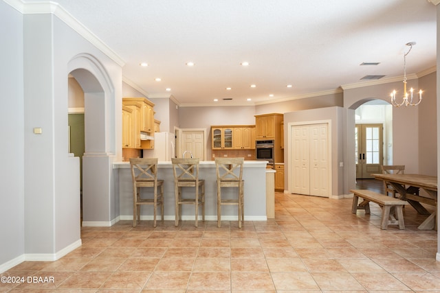 kitchen with white refrigerator, kitchen peninsula, oven, a chandelier, and a breakfast bar