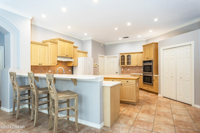 kitchen with light brown cabinetry, white refrigerator, tasteful backsplash, and a kitchen island with sink