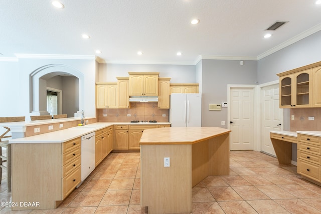 kitchen featuring a center island, light brown cabinets, a kitchen breakfast bar, tasteful backsplash, and white appliances