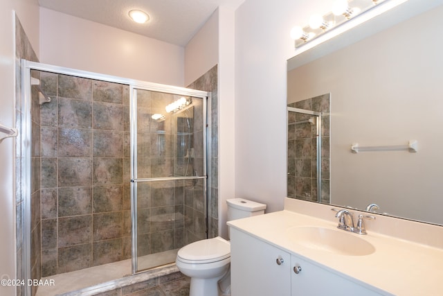 bathroom featuring tile patterned flooring, a textured ceiling, toilet, vanity, and a shower with shower door