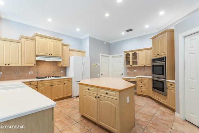 kitchen with appliances with stainless steel finishes, light brown cabinets, a kitchen island, and backsplash