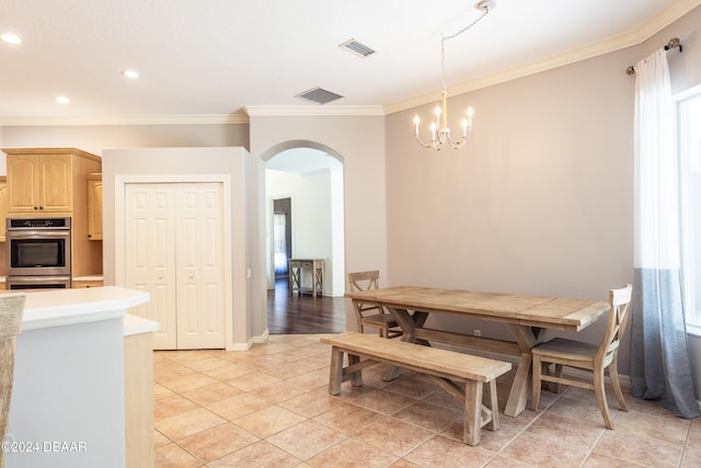 tiled dining space with an inviting chandelier, plenty of natural light, and ornamental molding