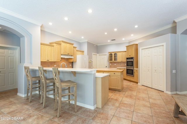 kitchen with light brown cabinets, white refrigerator, a center island with sink, and tasteful backsplash