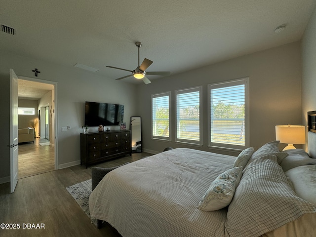 bedroom featuring ceiling fan, multiple windows, and dark hardwood / wood-style floors