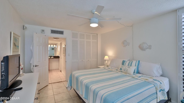 bedroom with light tile patterned floors, a closet, a textured ceiling, and visible vents