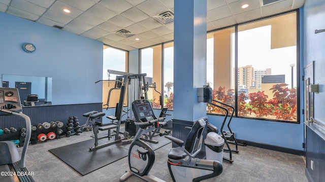 exercise room featuring a paneled ceiling, a healthy amount of sunlight, and visible vents