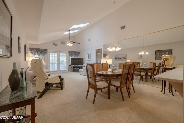 dining room with french doors, ceiling fan with notable chandelier, light carpet, high vaulted ceiling, and a skylight