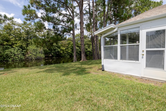 view of yard featuring a water view and a sunroom