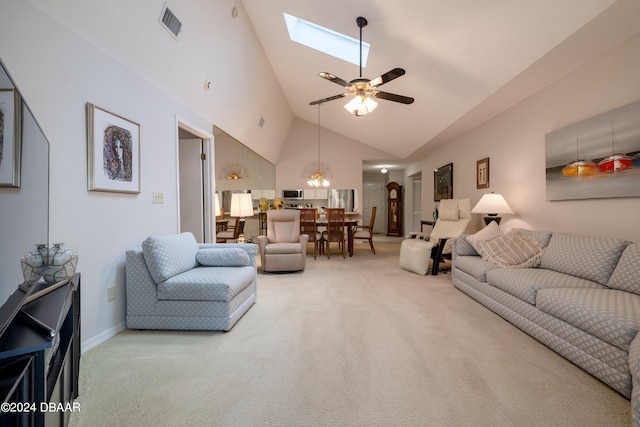 carpeted living room featuring high vaulted ceiling, a skylight, and ceiling fan with notable chandelier