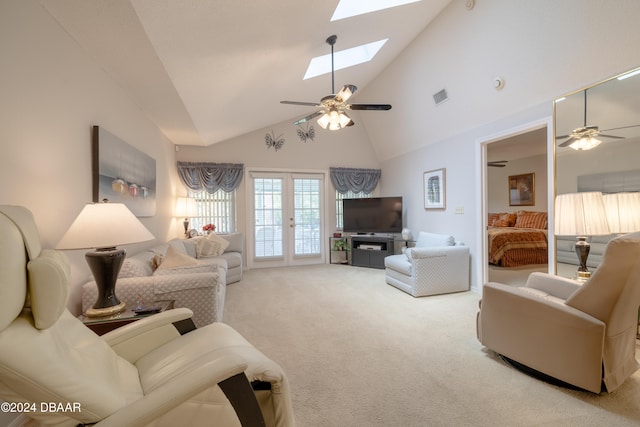 living room featuring ceiling fan, a skylight, high vaulted ceiling, light colored carpet, and french doors