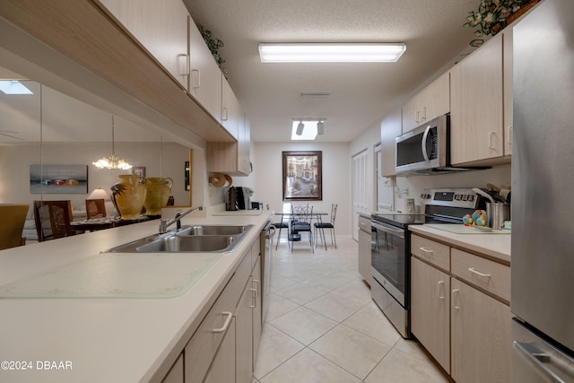 kitchen featuring stainless steel appliances, a textured ceiling, sink, and decorative light fixtures