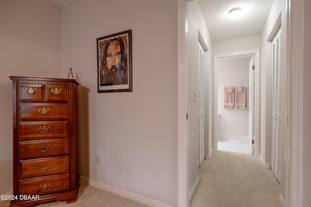 corridor featuring a textured ceiling and light colored carpet