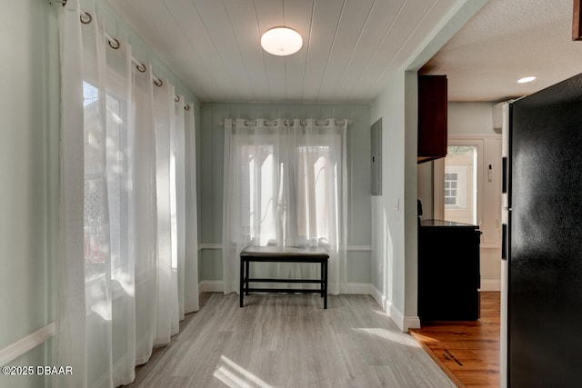 doorway with baseboards, wood finished floors, and electric panel
