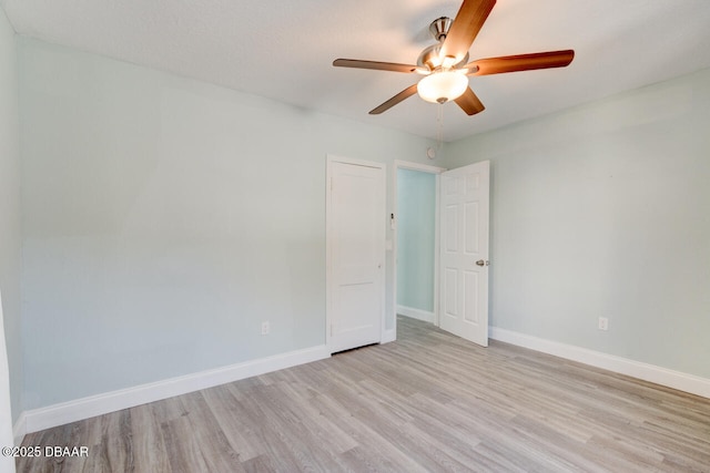 spare room featuring light wood-type flooring, baseboards, and ceiling fan