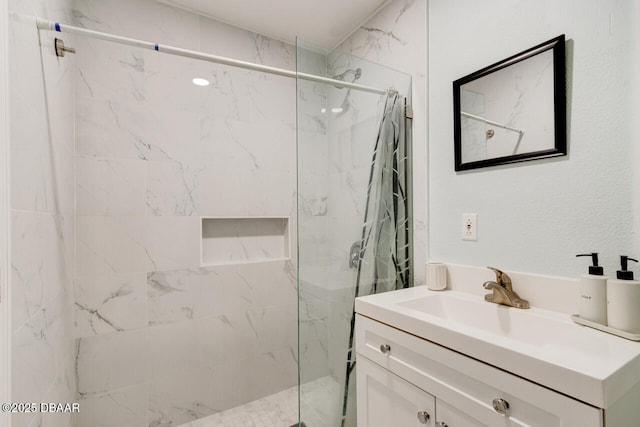 full bath featuring a marble finish shower and vanity