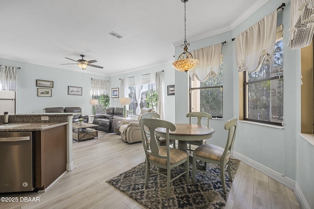 dining room with light wood-style flooring, visible vents, baseboards, a ceiling fan, and ornamental molding