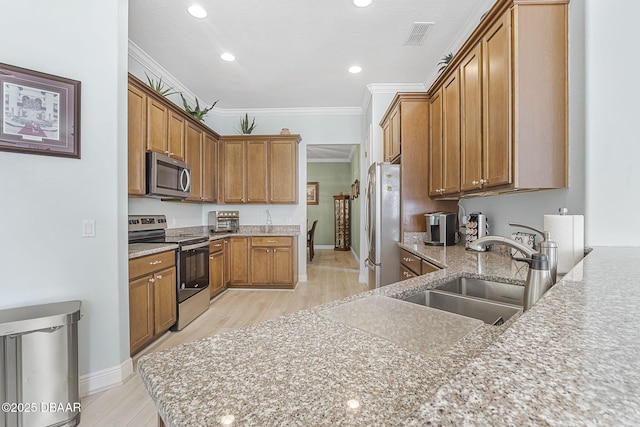 kitchen with appliances with stainless steel finishes, brown cabinets, a sink, and ornamental molding