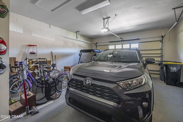 garage featuring concrete block wall and a garage door opener