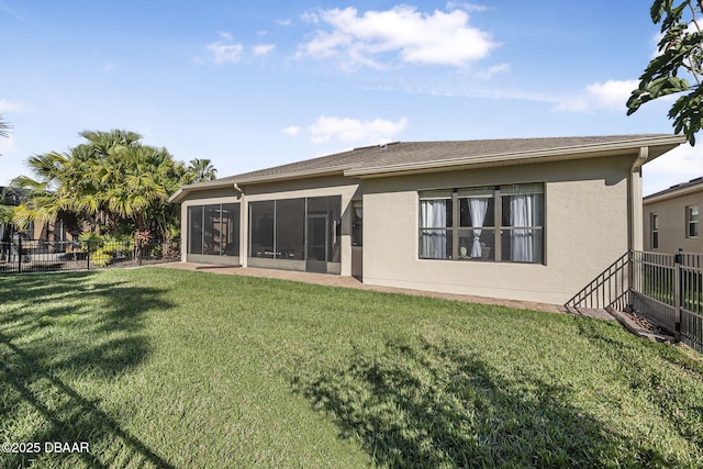 back of house featuring a lawn, fence, a sunroom, and stucco siding