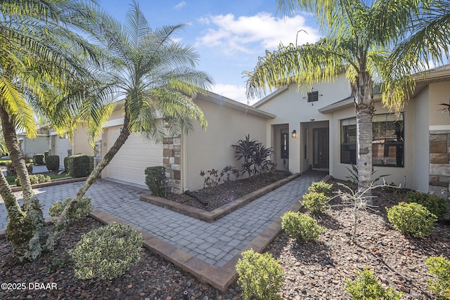 exterior space with decorative driveway, an attached garage, and stucco siding