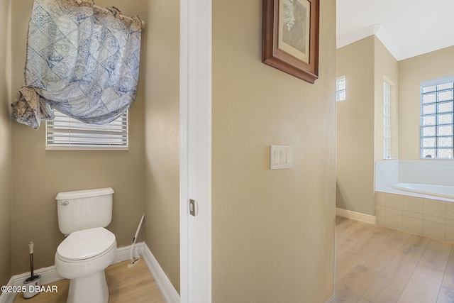 full bathroom featuring a garden tub, wood finished floors, toilet, and crown molding