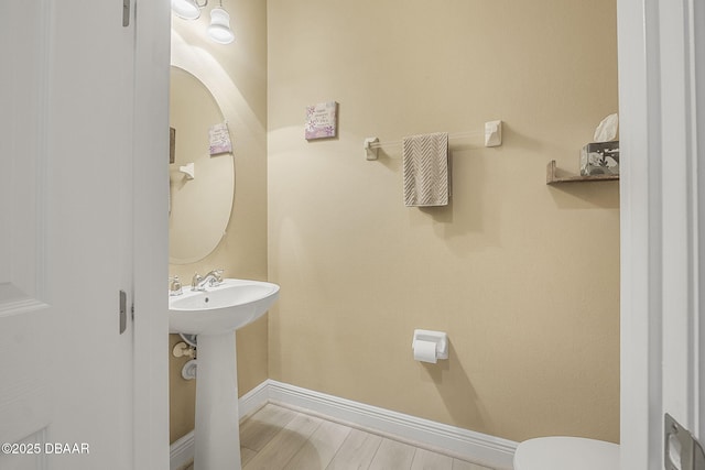 bathroom featuring wood finished floors, toilet, and baseboards