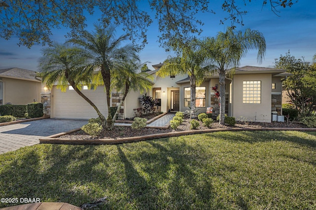 view of front of property with an attached garage, stone siding, decorative driveway, stucco siding, and a front lawn