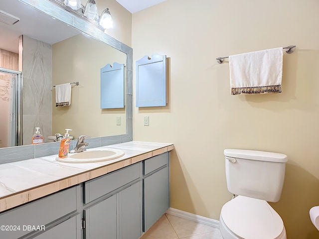 bathroom with toilet, vanity, tile patterned floors, and a shower with door