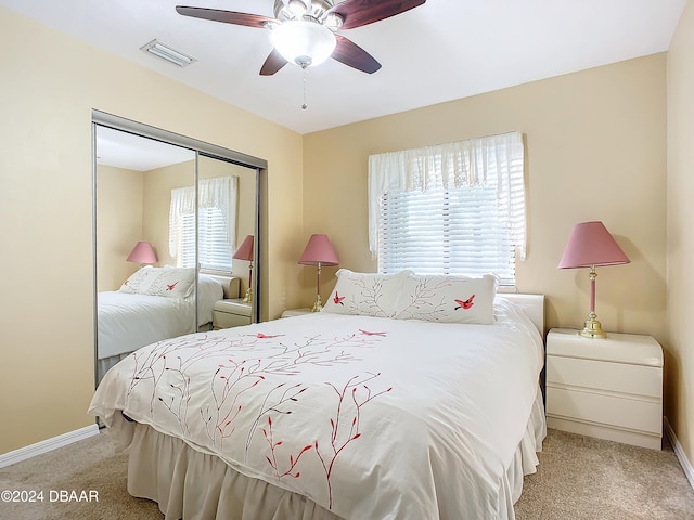 carpeted bedroom featuring multiple windows, ceiling fan, and a closet