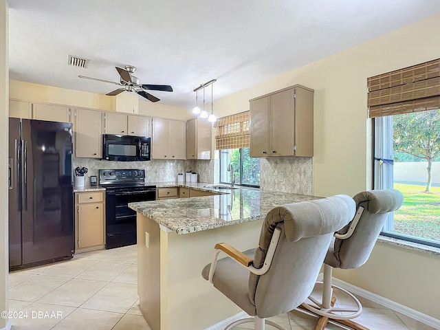 kitchen featuring black appliances, tasteful backsplash, a kitchen bar, sink, and kitchen peninsula