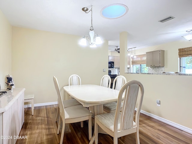 dining area featuring ceiling fan with notable chandelier and dark hardwood / wood-style floors