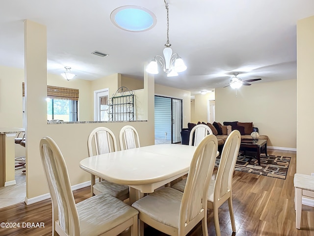 dining room with light hardwood / wood-style floors and ceiling fan with notable chandelier