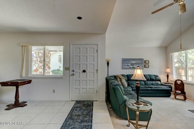 foyer entrance with baseboards, ceiling fan, a textured ceiling, tile patterned floors, and vaulted ceiling