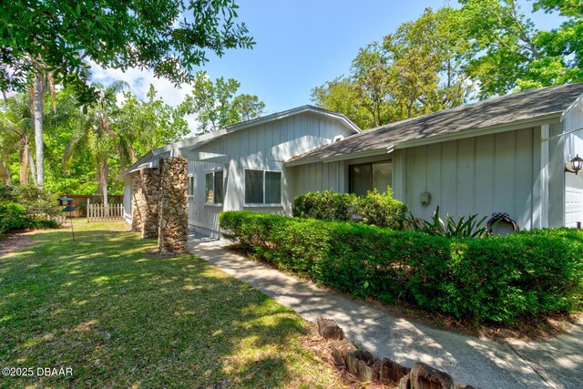 view of side of home with a lawn and fence