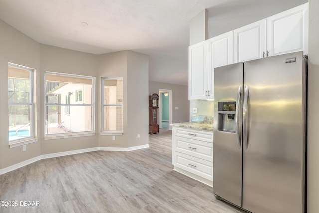3931 Tano Dr, Ormond Beach, FL 32174 - kitchen with stainless steel refrigerator with ice dispenser, light wood finished floors, white cabinets, baseboards, and light stone countertops