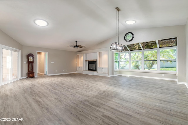 3931 Tano Dr, Ormond Beach, FL 32174 - unfurnished living room featuring ceiling fan, lofted ceiling, wood finished floors, baseboards, and a chandelier