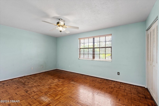 unfurnished bedroom with dark parquet floors, a textured ceiling, and ceiling fan