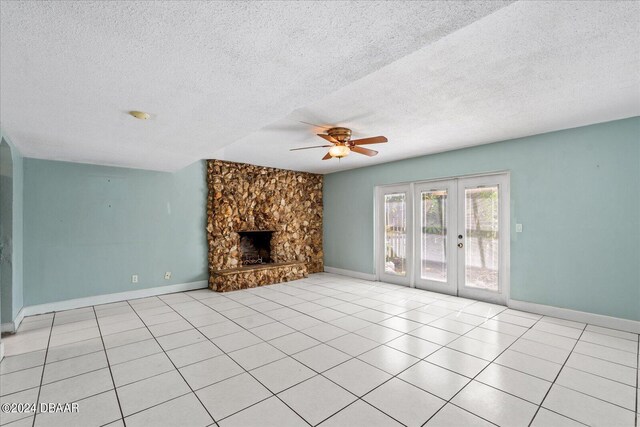 unfurnished living room featuring a fireplace, a textured ceiling, ceiling fan, and light tile patterned floors