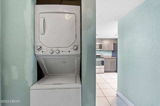 washroom with stacked washer / drying machine and light tile patterned floors