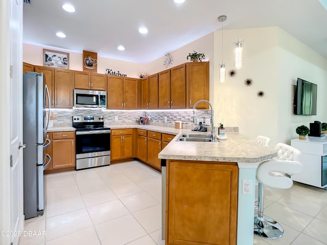 kitchen featuring pendant lighting, sink, appliances with stainless steel finishes, tasteful backsplash, and kitchen peninsula