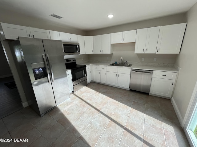 kitchen with stainless steel appliances, white cabinets, and sink