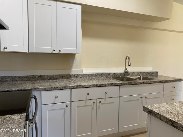 kitchen with stainless steel stove, white cabinetry, and sink