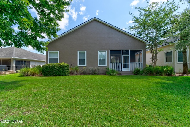 rear view of house with a sunroom and a yard