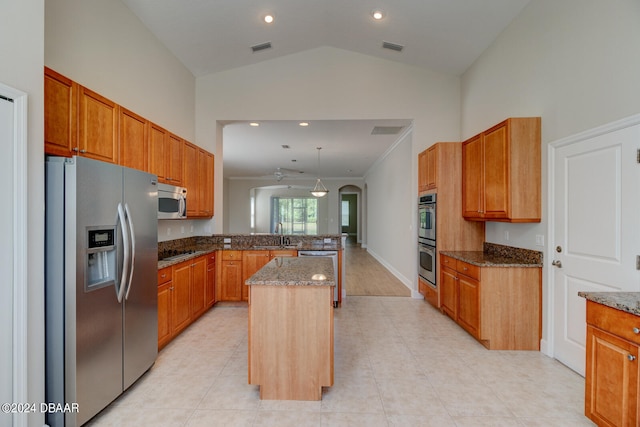 kitchen with lofted ceiling, sink, a kitchen island, appliances with stainless steel finishes, and dark stone countertops