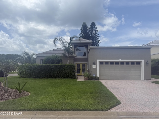 55 Bay Pointe Dr, Ormond Beach, FL 32174 - view of front of house featuring french doors, stucco siding, decorative driveway, a garage, and a front lawn