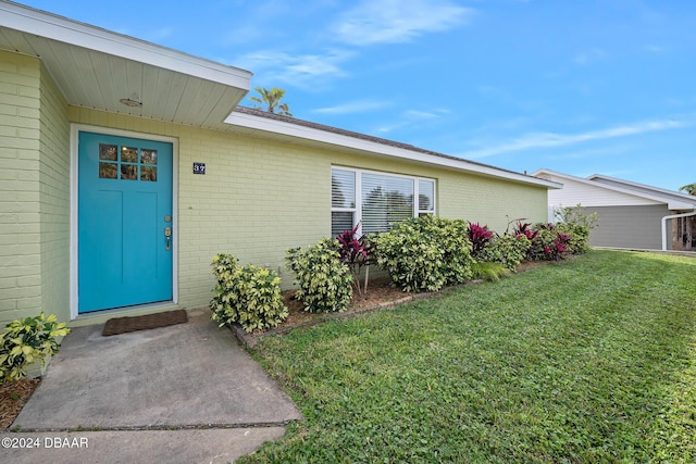 view of exterior entry featuring a lawn